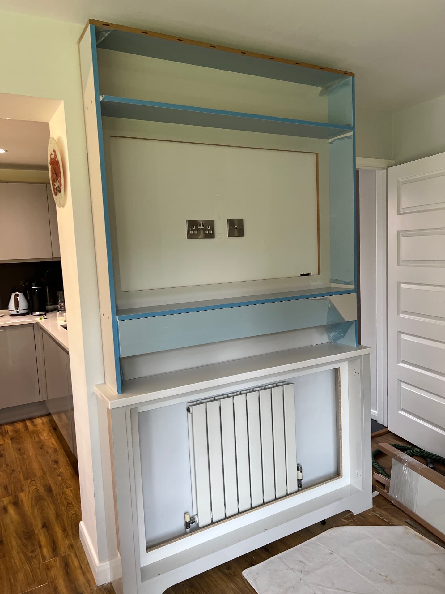 Unit carcass built around the radiator with shelving above