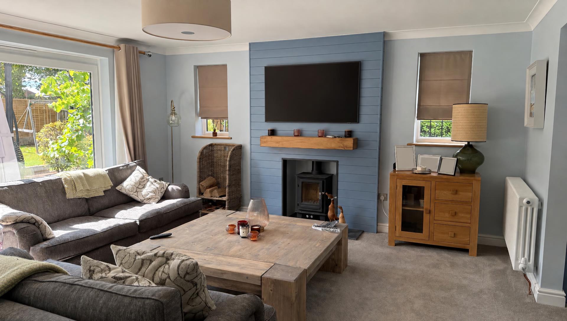 Panelled TV wall with art TV, oak shelf and log burner in the finished living room