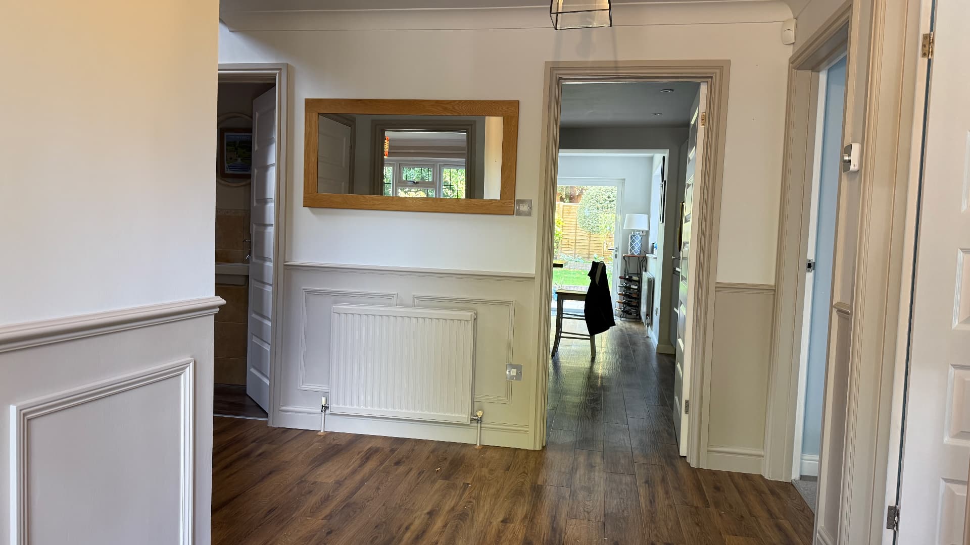 Completed hallway with bespoke wall panelling and oak-framed mirror